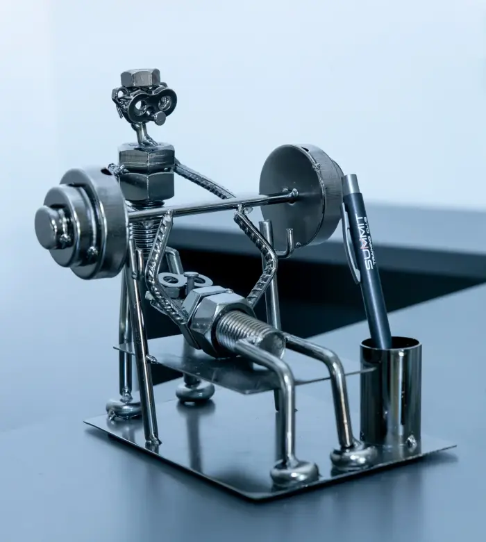 Statuina in metallo di un atleta che fa chest press assistito da un compagno.